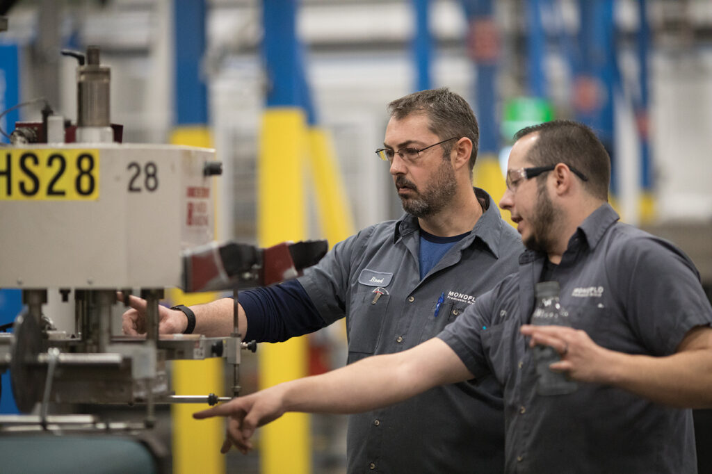 Two men engaged in machine work at a factory, representing partnership and progress in the local community.