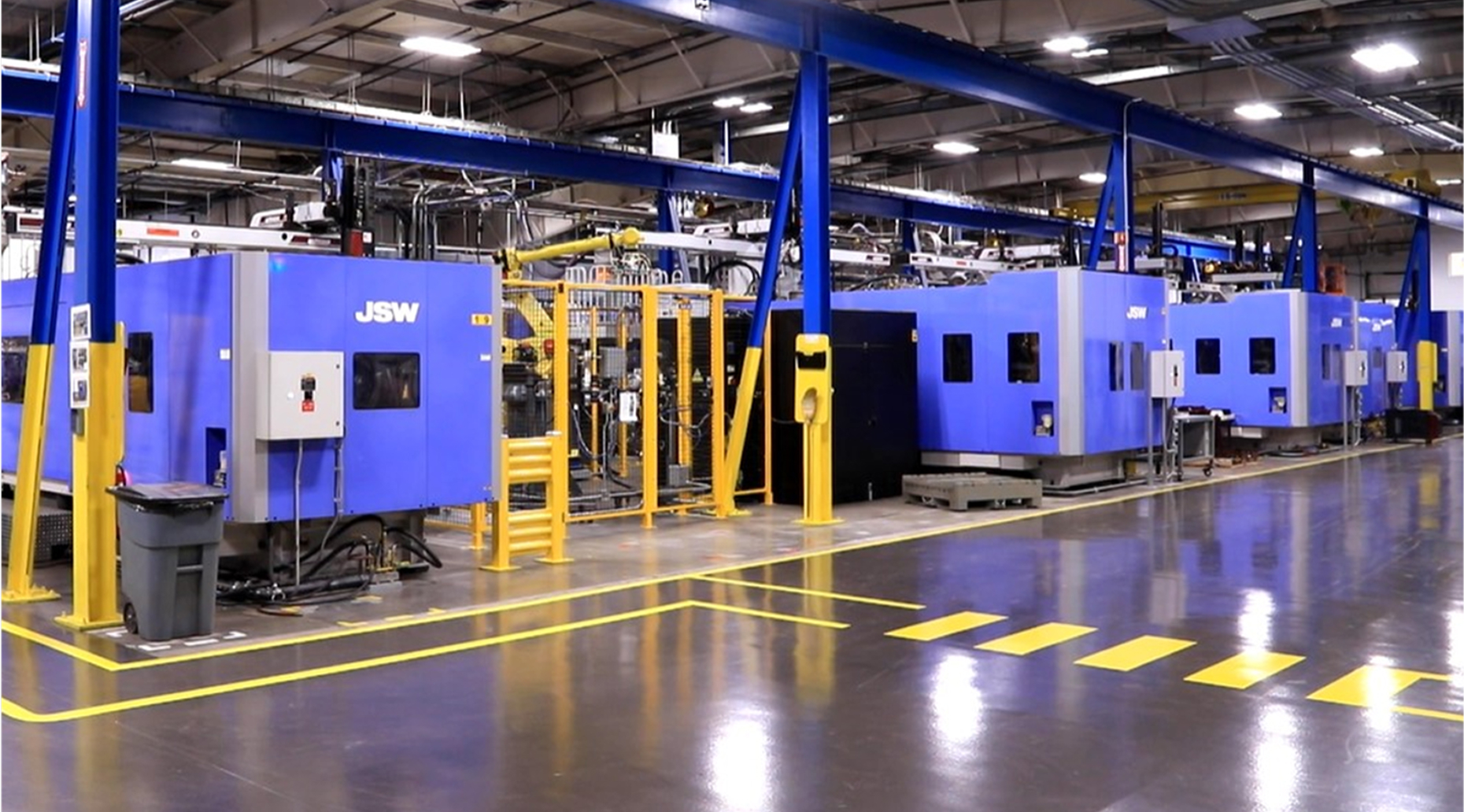 Row of large blue JSW industrial machines inside a clean, well-lit manufacturing facility.