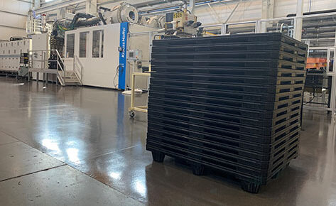 A vast warehouse containing multiple black pallets, engineered for durability in downstream grocery distribution.